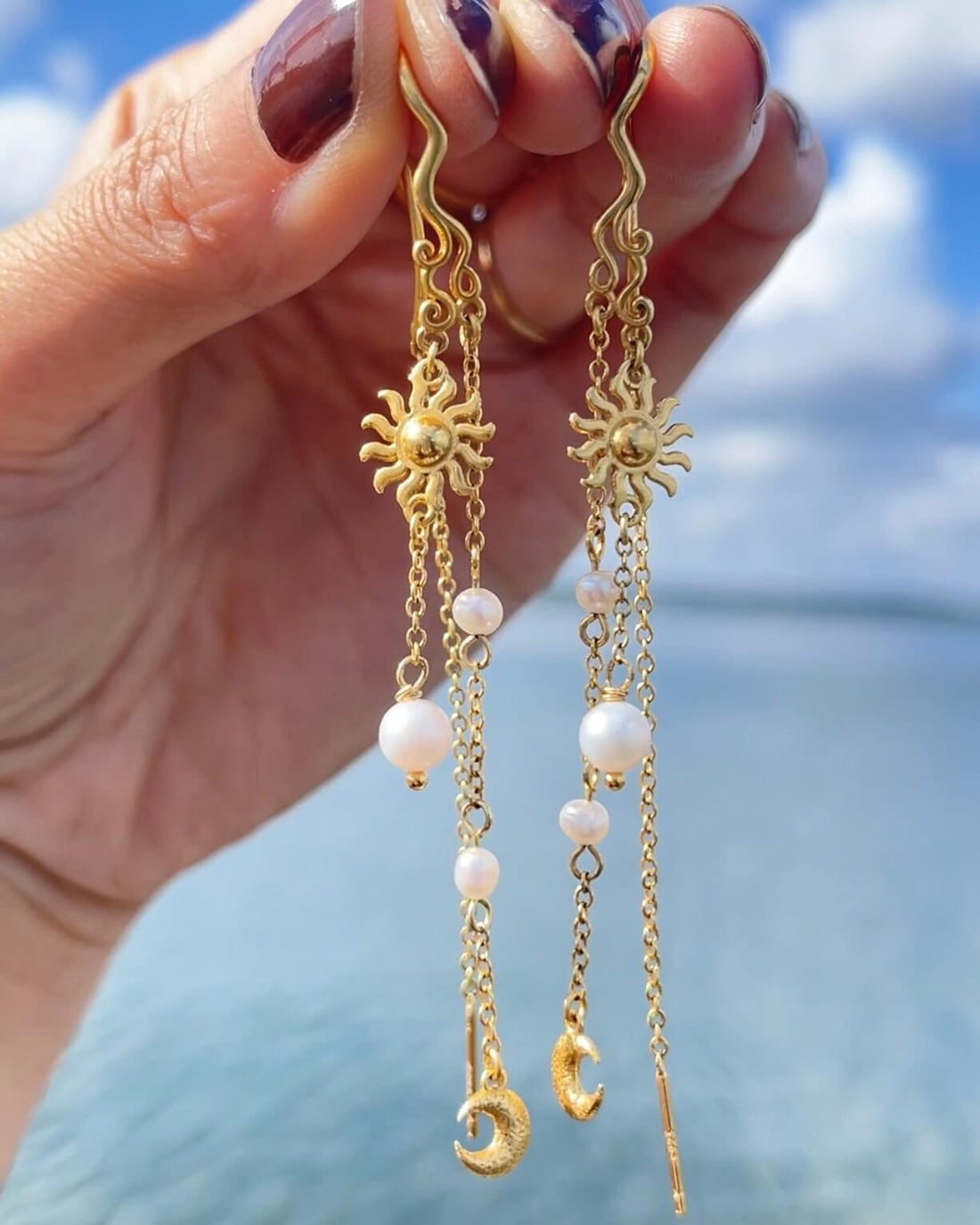 Pallantis Smykkers Måne Perle Øreringe er forgyldte sølvøreringe med asymmetriske sol- og halvmånevedhæng, fine kæder prydet med ferskvandsperler og en bølget topstilk for et elegant og dekorativt touch.